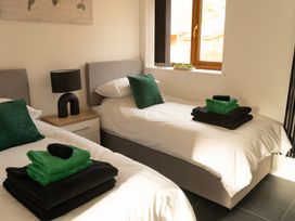 A bedroom with two single beds green and black towels on beds and a bedside table with a lamp at The Green Monkey in North Hykeham