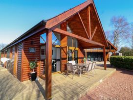 An outdoor wooden deck with a table and six chairs in front of a wooden cabin at The Green Monkey in North Hykeham