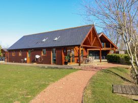 A wooden house with a patio and outdoor furniture on a grass lawn with a gravel path at The Green Monkey in North Hykeham