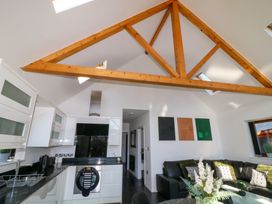 A kitchen and living area with wooden ceiling beams and a black leather sofa at The Green Monkey in North Hykeham