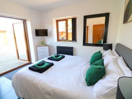 A bedroom with a bed with green pillows and folded towels a dresser a wall-mounted TV a mirror and an open door leading outside at The Green Monkey in North Hykeham