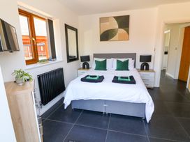 A bedroom with a double bed green pillows black lamps and a wall mirror at The Green Monkey in North Hykeham