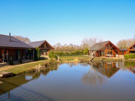 A pond with wooden cabins around it at The Green Monkey in North Hykeham