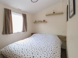 A bedroom with a bed covered in a heart patterned duvet and shelves above at 31B Foxburrow Hang in Fritton near Belton Norfolk