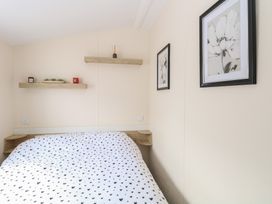A bedroom with a bed with heart patterned bedding wooden shelves with decorations and framed flower pictures on the wall at 31B Foxburrow Hang in Fritton near Belton Norfolk