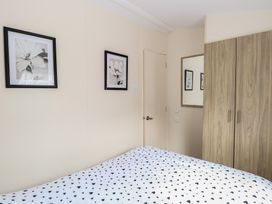 A bedroom with a bed covered in a heart patterned duvet two framed flower pictures on the wall a wooden wardrobe and a wall mirror at 31B Foxburrow Hang Fritton near Belton Norfolk