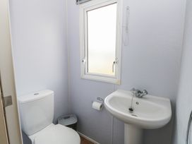 A bathroom with a toilet a pedestal sink a window and a trash bin at 31B Foxburrow Hang in Fritton near Belton Norfolk