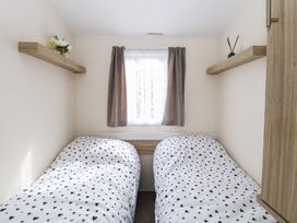 A bedroom with two single beds with heart-patterned bedding and two shelves with decorative items at 31B Foxburrow Hang in Fritton near Belton Norfolk