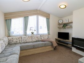 A living room with a sectional sofa and a television on shelves at 31B Foxburrow Hang in Fritton near Belton Norfolk