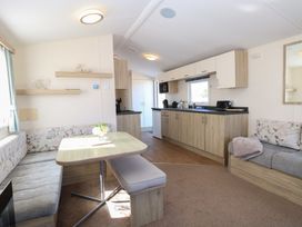 A kitchen and dining area with wooden cabinets and a table with a bench and upholstered seating at 31B Foxburrow Hang in Fritton near Belton Norfolk