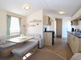 A kitchen and dining area with wooden cabinets and a table with seating at 31B Foxburrow Hang in Fritton near Belton Norfolk