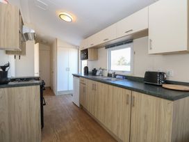 A kitchen with wooden floor and cabinets a window black toaster and microwave oven at 31B Foxburrow Hang in Fritton near Belton Norfolk