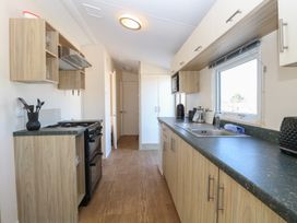 A kitchen with wooden cabinets a black gas stove a sink and a window at 31B Foxburrow Hang in Fritton near Belton Norfolk
