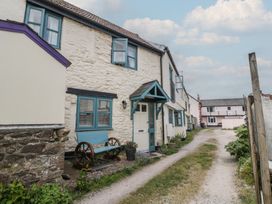 An exterior view of a stone house with blue window frames and a bench beside the front door at 1 The Mews in Porlock