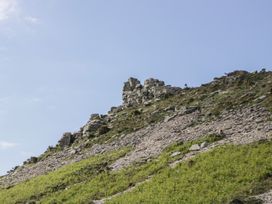 A rocky hillside with scattered grass and bushes under a clear sky at 1 The Mews in Porlock