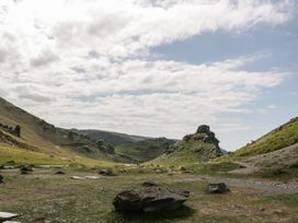 A valley with rocky hills paths and scattered rocks under a cloudy sky at 1 The Mews in Porlock