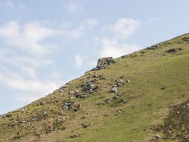 A grassy hillside with scattered rocks under a cloudy sky at 1 The Mews in Porlock