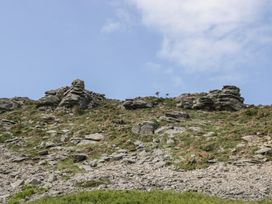 A rocky hillside with scattered grass and small shrubs under a partly cloudy sky at 1 The Mews in Porlock