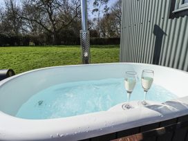 An outdoor hot tub with two glasses of champagne and a grassy field in the background at Buttercup in Ashby-cum-Fenby near Waltham