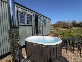 A hot tub and outdoor table with chairs outside a corrugated cabin at Buttercup in Ashby-cum-Fenby near Waltham