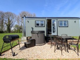 An outdoor area with a grill table chairs and a hot tub in front of a corrugated metal building at Buttercup in Ashby-cum-Fenby near Waltham