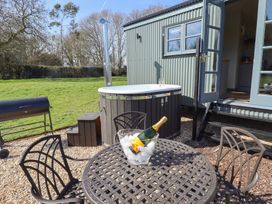 An outdoor seating area with a round table and chairs a bottle of champagne on ice a hot tub next to a small building at Buttercup in Ashby-cum-Fenby near Waltham