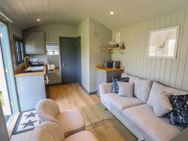 A small living area with two chairs a sofa with pillows a glass coffee table and a kitchenette at Buttercup Ashby-cum-Fenby near Waltham