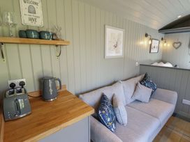 A couch with cushions next to a wooden countertop with a toaster and kettle in a room with framed pictures and a welcome sign at Buttercup in Ashby-cum-Fenby near Waltham