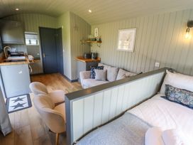 A small living space with a bed separated by a partition from a sitting area with a sofa and chairs and a kitchenette at Buttercup in Ashby-cum-Fenby near Waltham