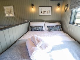 A bed with white linens and blue patterned pillows in a small room with gray paneled walls at Buttercup in Ashby-cum-Fenby near Waltham