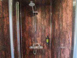 A shower with a mounted shower head and a bottle of soap inside a glass enclosure at Buttercup in Ashby-cum-Fenby near Waltham
