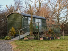 A green wooden cabin with a ramp and a deck surrounded by plants and trees at Perch Hut in Hadlow Down near Crowborough