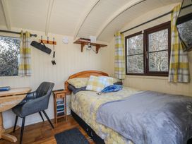 A bedroom with a bed pillows and blankets a chair and a small wooden table at Perch Hut in Hadlow Down near Crowborough