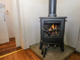 A wood burning stove with fire inside in a corner on a stone hearth at Perch Hut in Hadlow Down near Crowborough