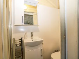 A small bathroom with a sink cabinet mirror toilet and towel holder at Perch Hut in Hadlow Down near Crowborough