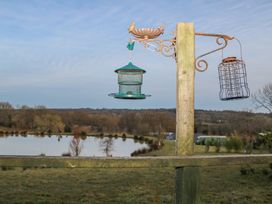 A bird feeder mounted on a wooden post overlooking a pond and countryside at Perch Hut in Hadlow Down near Crowborough