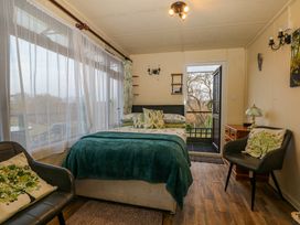 A bedroom with a bed a window two chairs and a door leading outside at Tench Hut in Hadlow Down near Crowborough