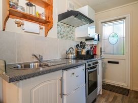 A kitchen with a sink stove refrigerator and utensils near a door at Tench Hut in Hadlow Down near Crowborough