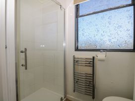 A bathroom with a shower cubicle a heated towel rail a frosted window and a toilet roll holder at Tench Hut in Hadlow Down near Crowborough
