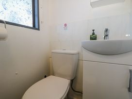 A small bathroom with a toilet and a white sink cabinet under a frosted window at Tench Hut in Hadlow Down near Crowborough
