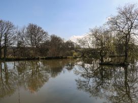 A pond surrounded by trees with reflections on the water at Carp Hut in Hadlow Down near Crowborough