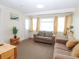 A living room with two sofas a small wooden table with a plant and a door with windows at Chalet 21 in Newport Norfolk