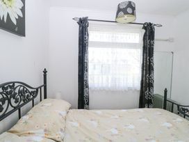 A bedroom with a bed with patterned bedding a window with curtains a wall mirror and a floral lampshade at Chalet 21 in Newport Norfolk