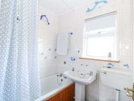 A bathroom with a bathtub sink toilet dolphin decorations and a window with a roller blind at Chalet 21 Newport Norfolk