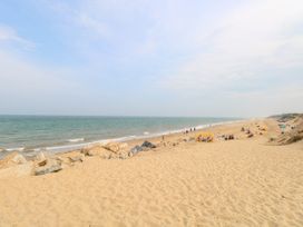 A sandy beach with people near the shoreline and rocks along the coast at Chalet 21 in Newport Norfolk