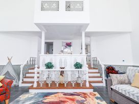 A living room with stairs and decorative railings leading to a dining area at Trelowth Chapel in Polgooth