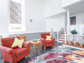 A sitting area with two patterned armchairs and a small wooden table in a room with white walls and tiled floor at Trelowth Chapel in Polgooth