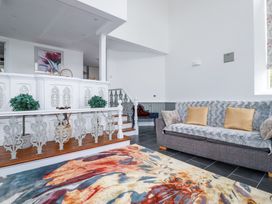 A living room with a gray sofa and a multicolored rug near stairs with decorative railing at Trelowth Chapel in Polgooth