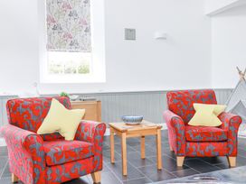 A seating area with two patterned armchairs and a wooden table at Trelowth Chapel in Polgooth