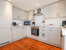 A kitchen with white cabinets wooden floor and appliances at Trelowth Chapel in Polgooth